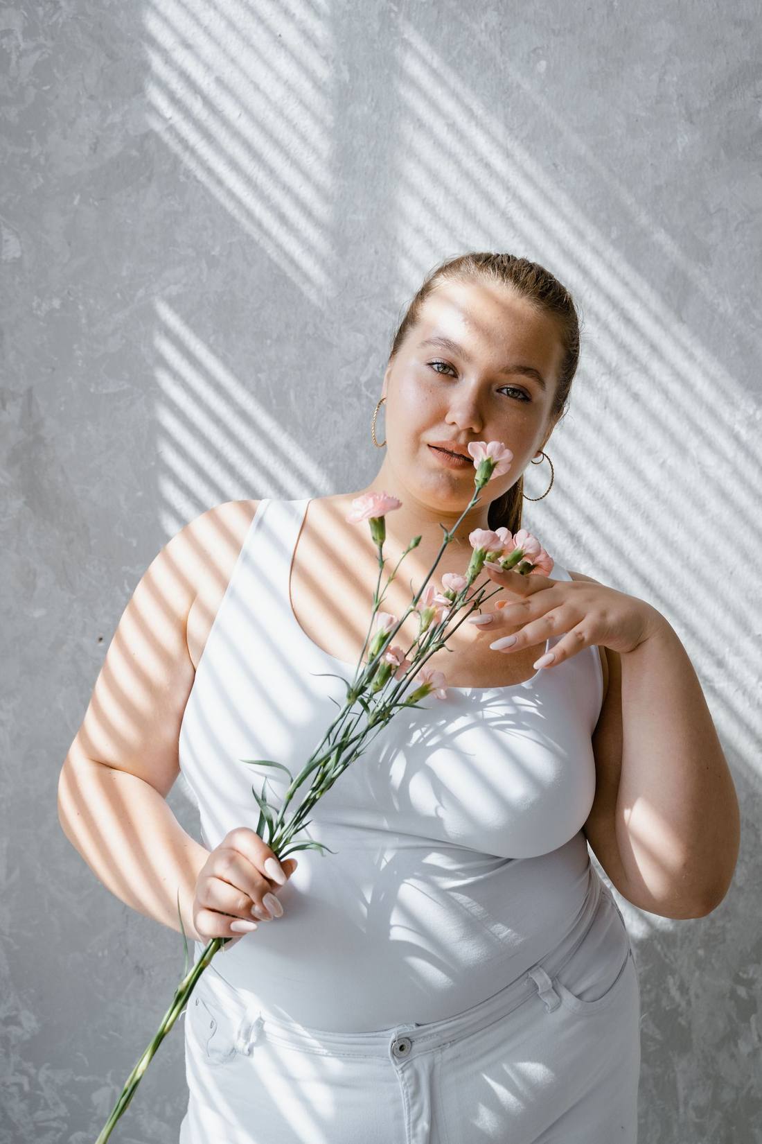 Mujer curvy sonriente con flores en Madrid, foto ilustrativa de stock, no representa a un miembro real